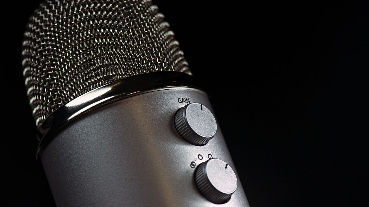Close-up of a silver studio microphone with its gain knob