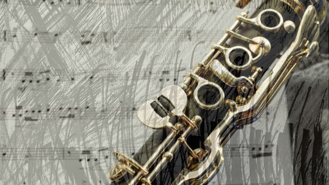 Close-up of clarinet keys and tone holes over sheet music
