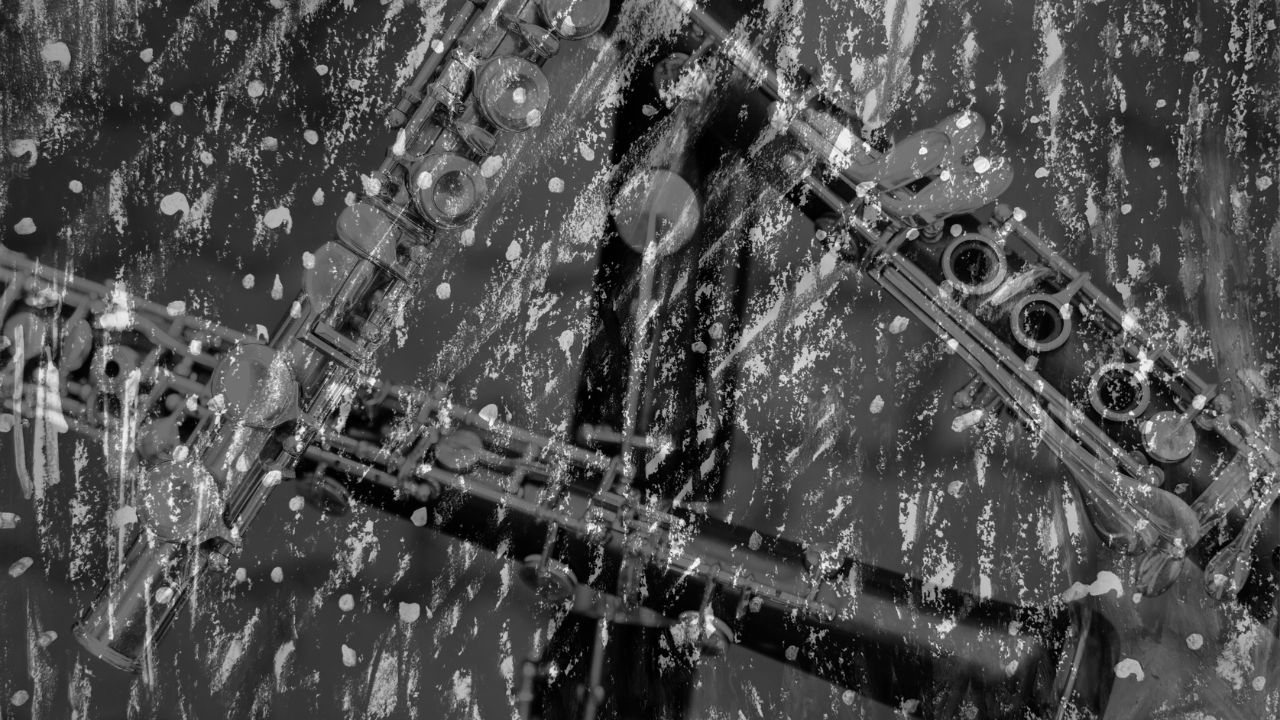 Black and white textured artwork of woodwind instruments such as flute and clarinet keywork