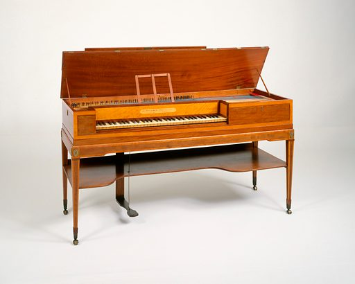 A wooden square piano with its lid raised, on tapered legs