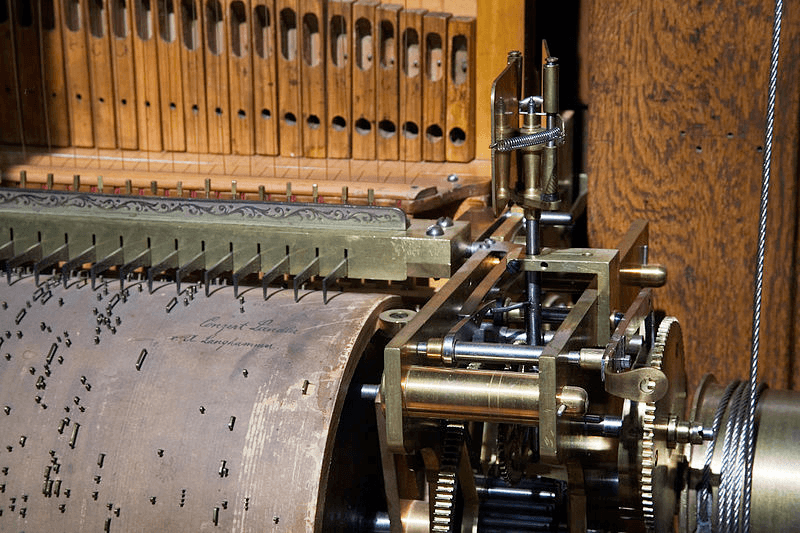 Close-up of an automatic piano's punched roll and the brass mechanism that reads it