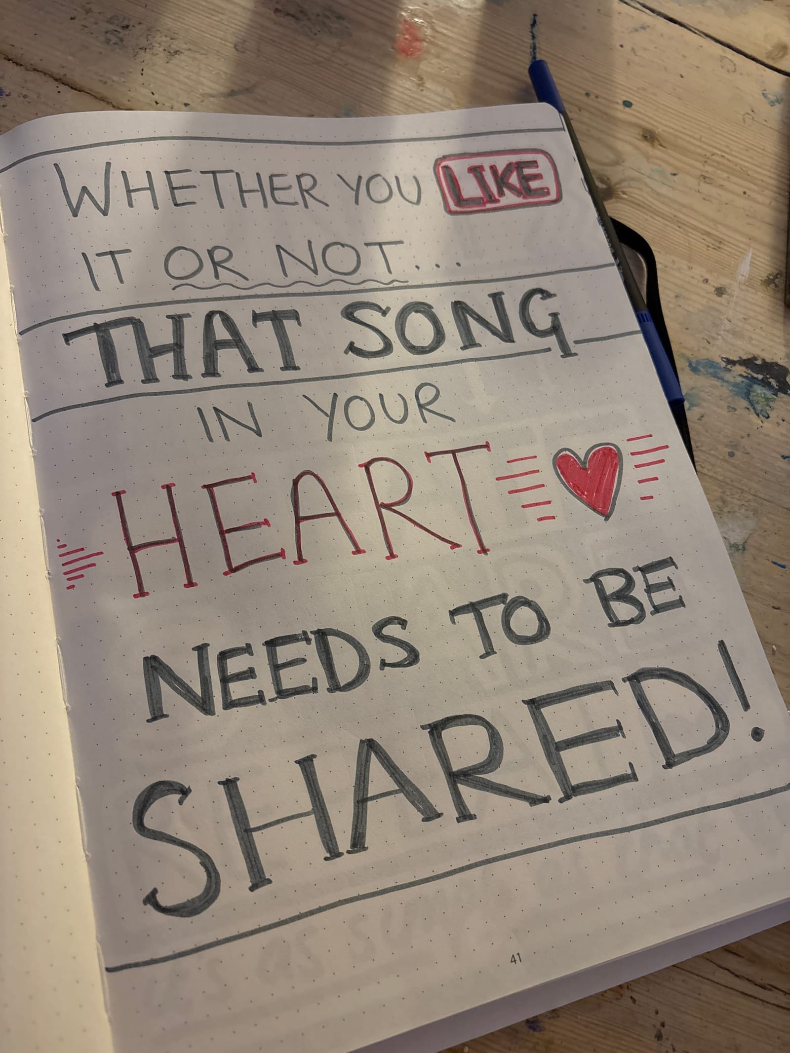 Hand-lettered notebook page reading Whether you like it or not, that song in your heart needs to be shared